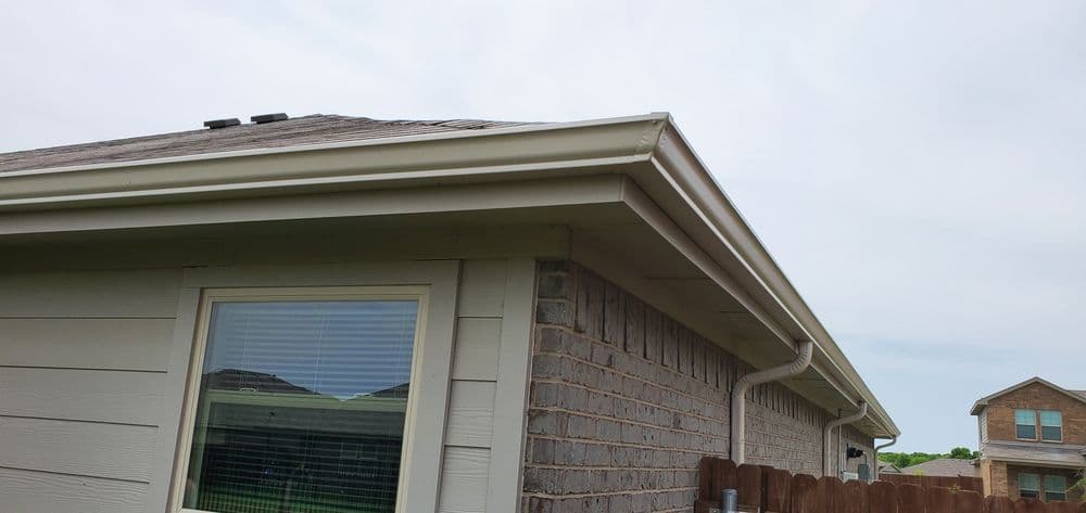 House exterior showing roofline, window, and neighboring home with cloudy sky.