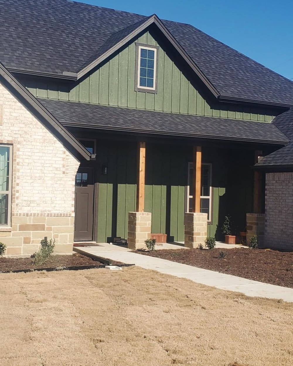 Modern green facade home with stone accents and landscaped front yard.