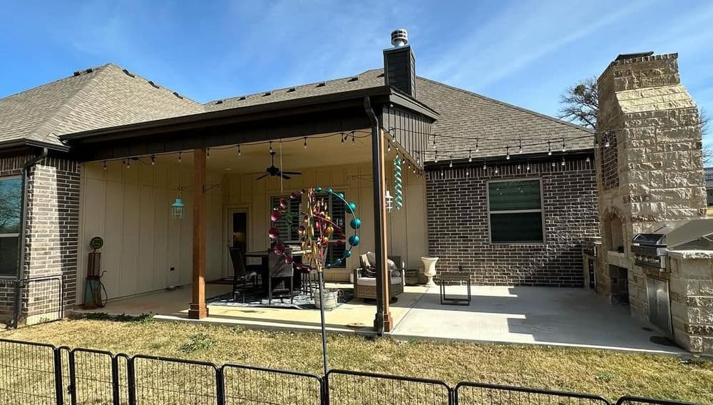 Backyard patio with outdoor seating, stone fireplace, and decorative elements on a sunny day.