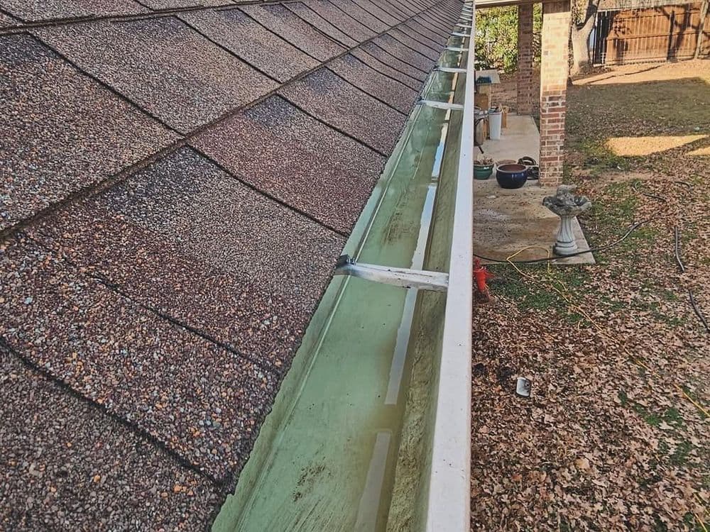 Clogged gutter filled with water and leaves on a sloped roof.
